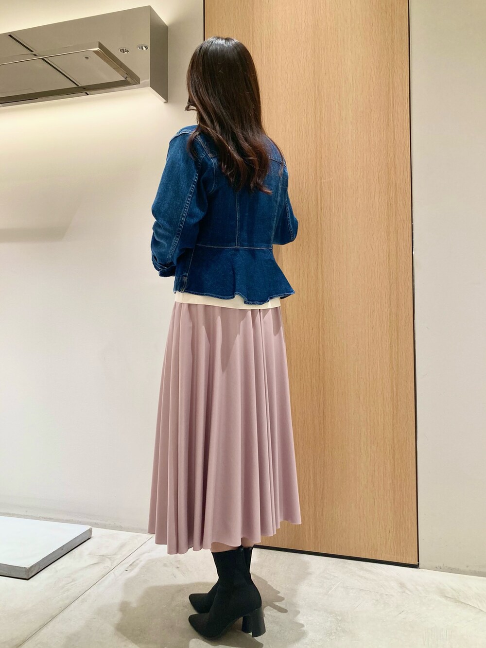 ブルー系のデニムジャケット、ホワイト系のニット/セーター、ピンク系のスカートを着用したレディースの秋コーディネートの4枚目の写真