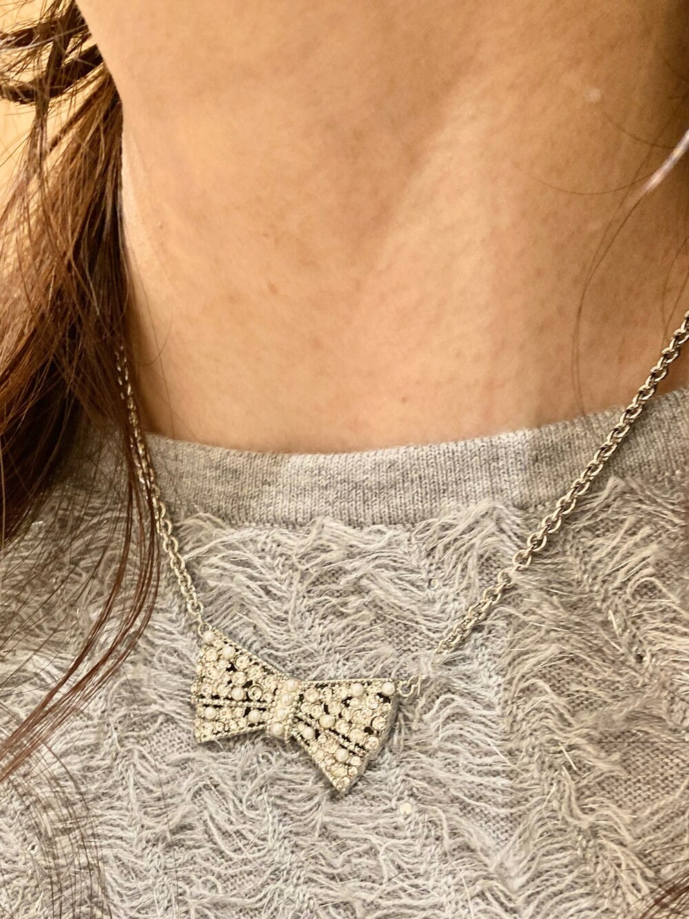 グレー系のニット/セーター、ホワイト系のスカート、シルバー系のネックレスを着用したレディースの秋コーディネートの7枚目の写真