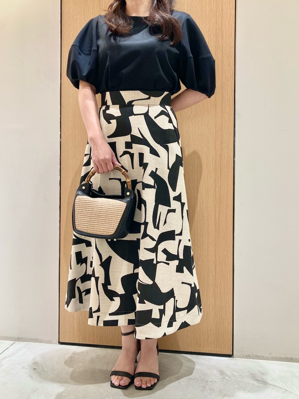 ブラック系のTシャツ/カットソー、ベージュ系のスカート、ブラック系のハンドバッグを着用したレディースの春コーディネートの4枚目の写真