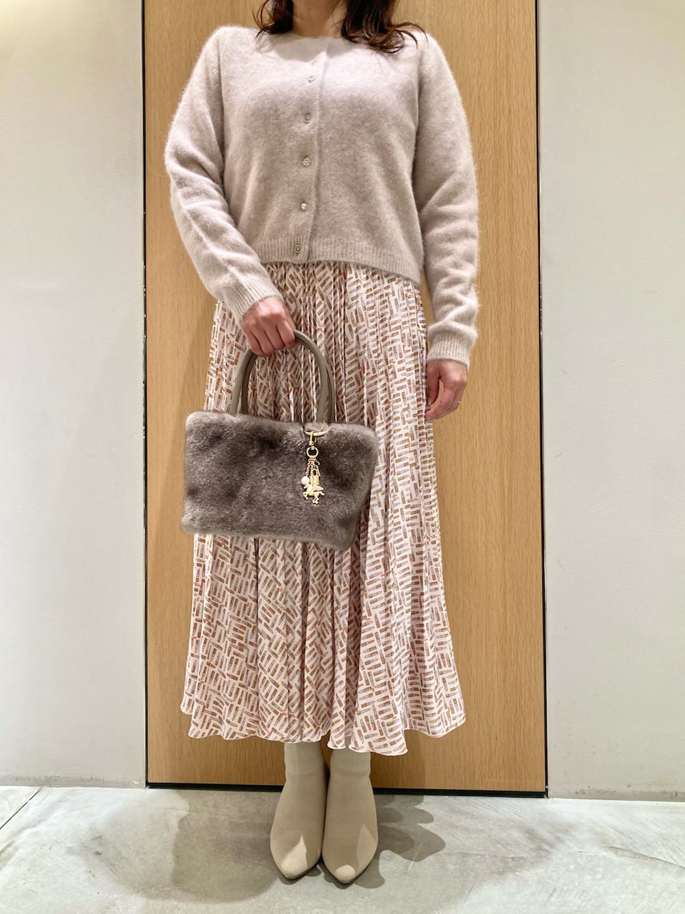 ピンク系のカーディガン/ボレロ、ベージュ系のスカート、ベージュ系のハンドバッグを着用したレディースの秋コーディネートの4枚目の写真