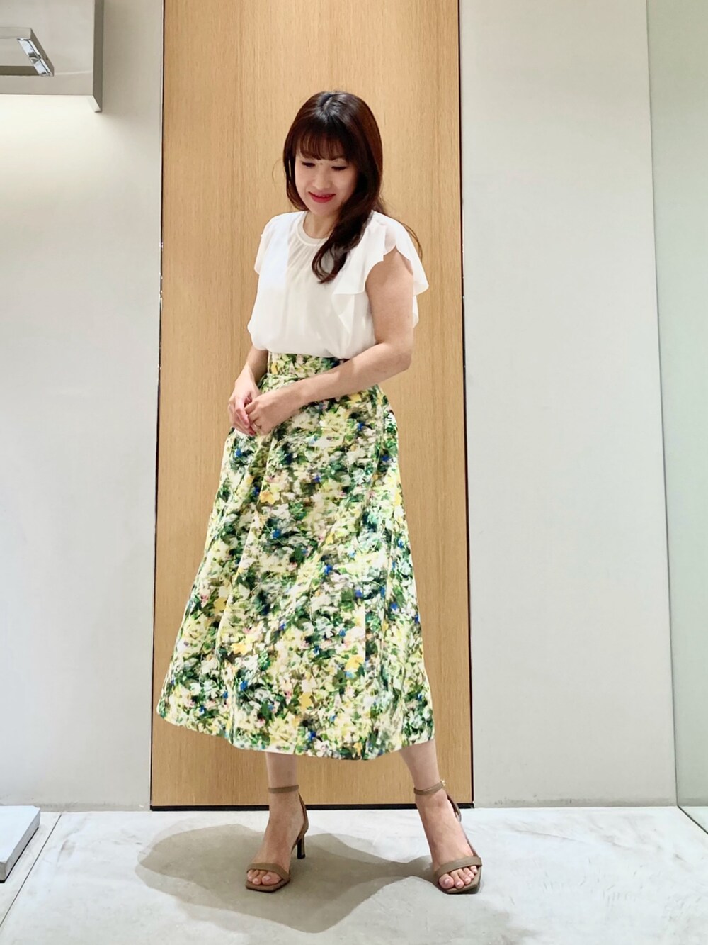 ホワイト系のその他トップス、グリーン系のスカート、ゴールド系のイヤリングを着用したレディースの夏コーディネートの2枚目の写真