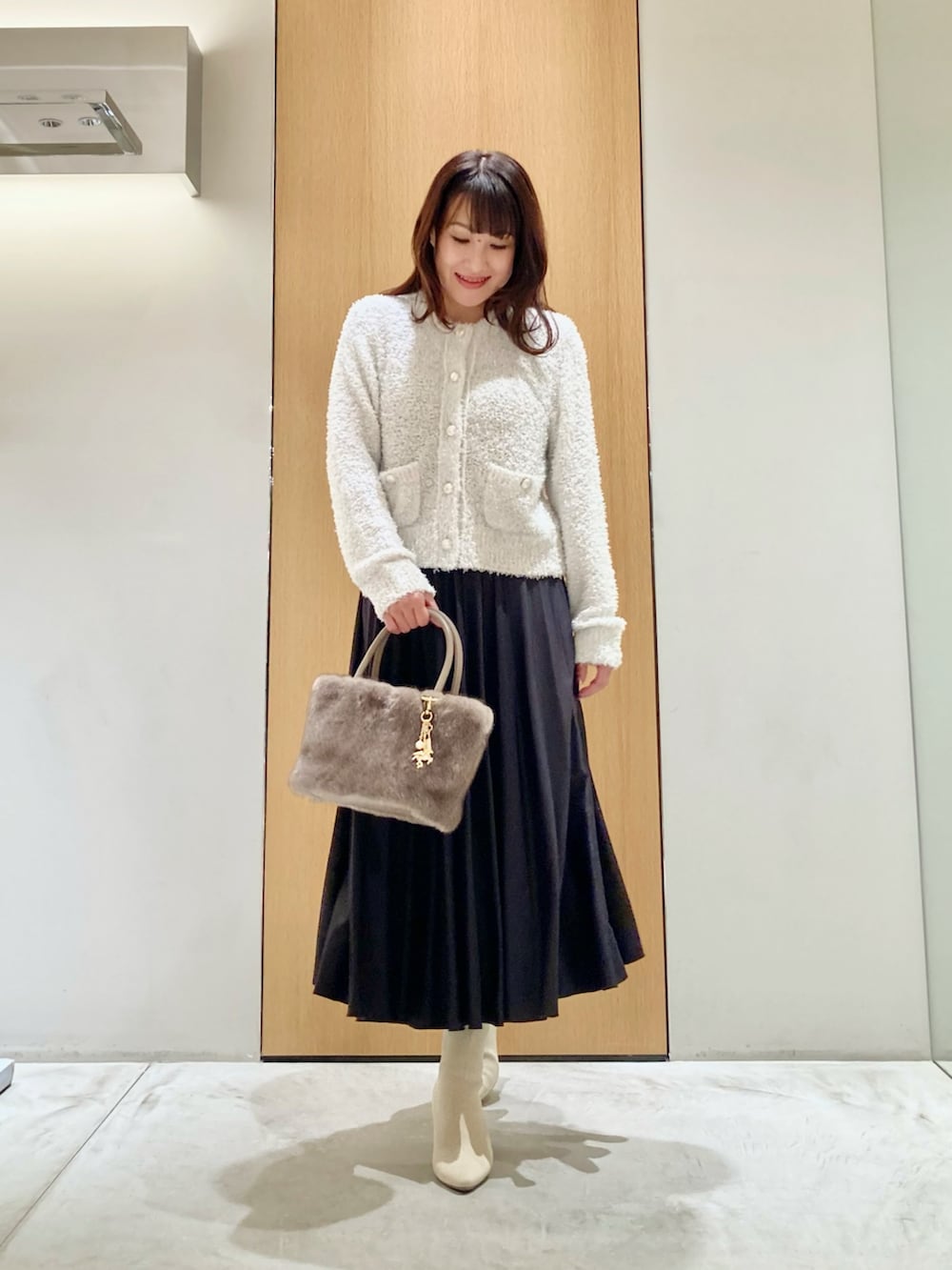 ホワイト系のカーディガン/ボレロ、ベージュ系のハンドバッグ、グレー系のスカートを着用したレディースの秋コーディネートの2枚目の写真