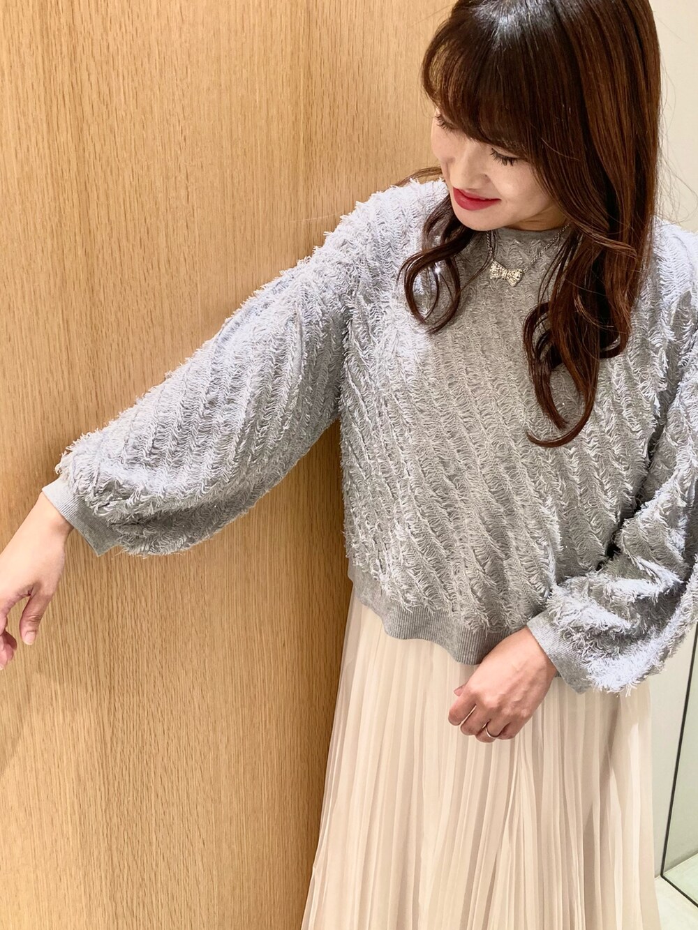 グレー系のニット/セーター、ホワイト系のスカート、シルバー系のネックレスを着用したレディースの秋コーディネートの6枚目の写真