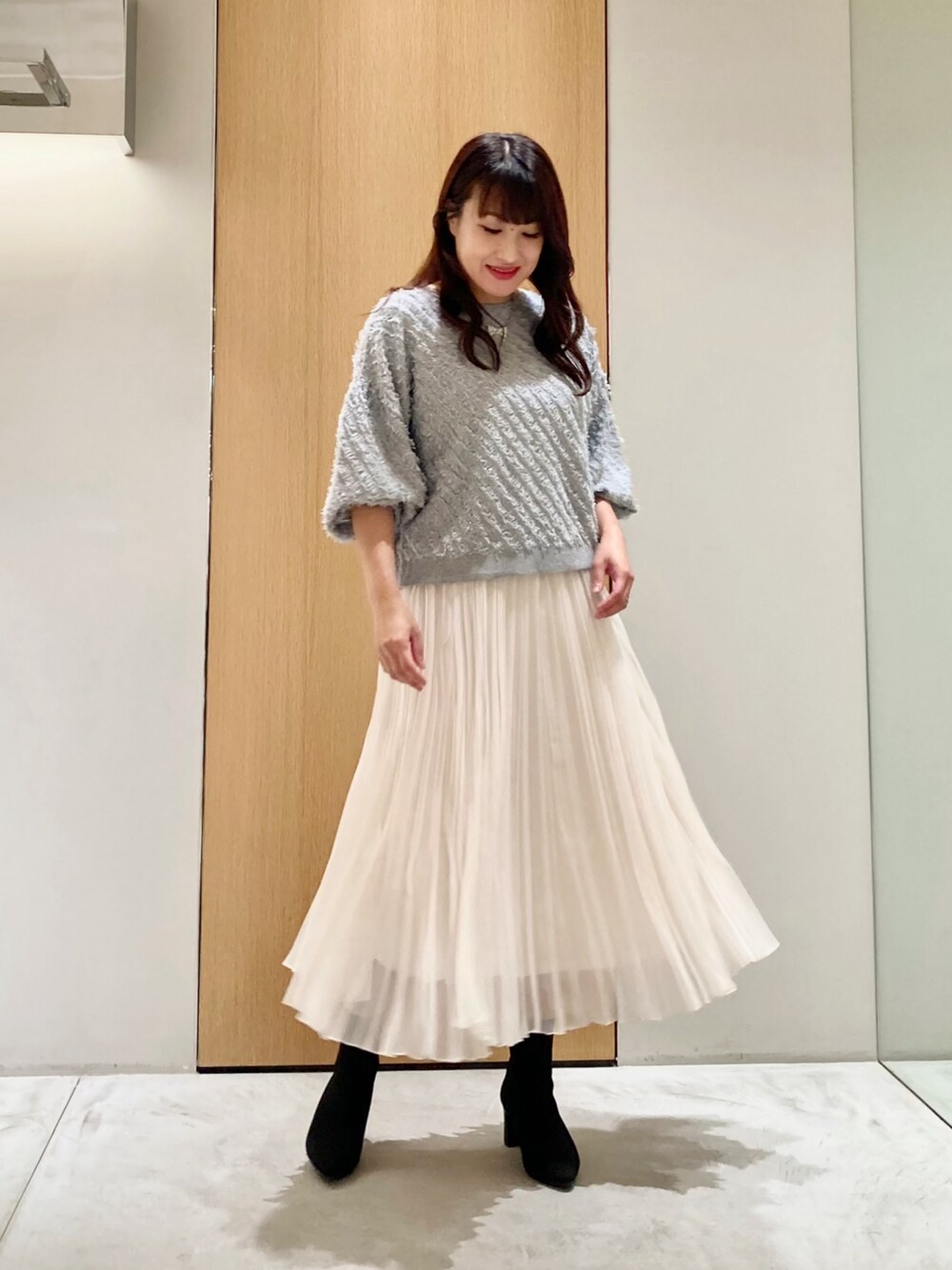 グレー系のニット/セーター、ホワイト系のスカート、シルバー系のネックレスを着用したレディースの秋コーディネートの3枚目の写真