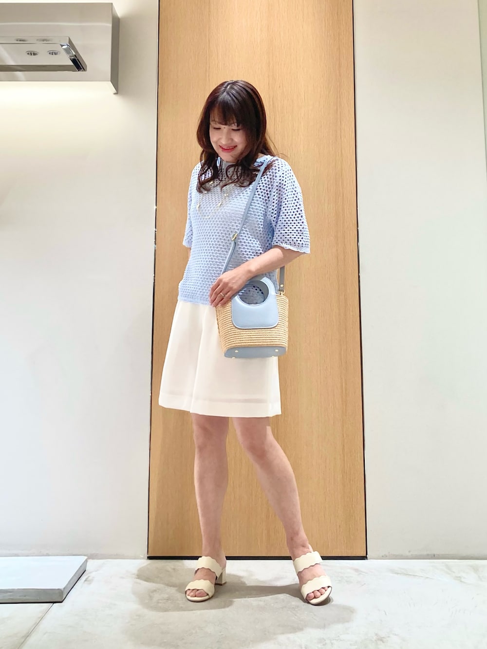 ブルー系のニット/セーター、ホワイト系のその他パンツ、ブルー系のハンドバッグを着用したレディースの夏コーディネートの2枚目の写真
