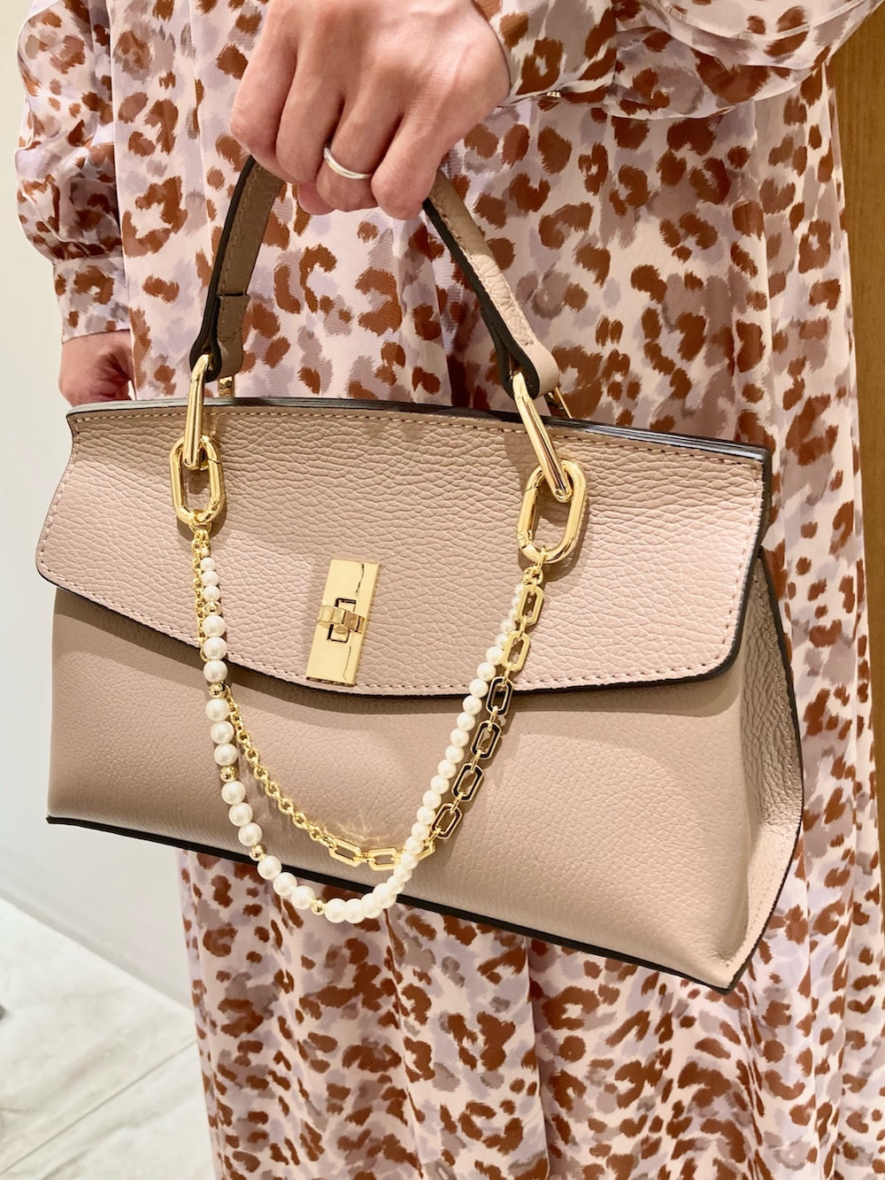 グレー系のワンピース、ピンク系のハンドバッグ、ゴールド系のリングを着用したレディースの秋コーディネートの7枚目の写真