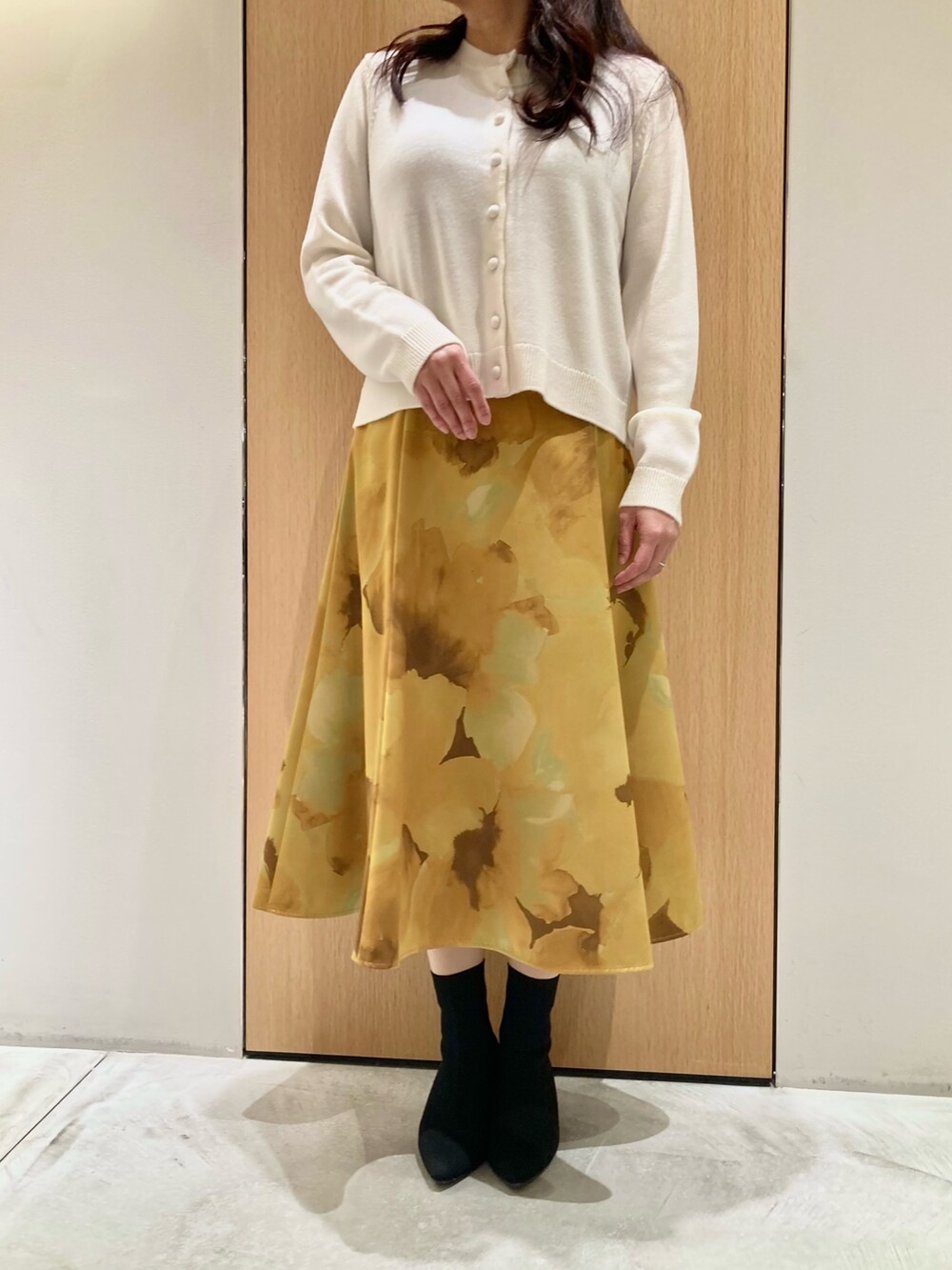 ホワイト系のカーディガン/ボレロ、イエロー系のスカートを着用したレディースの秋コーディネートの5枚目の写真