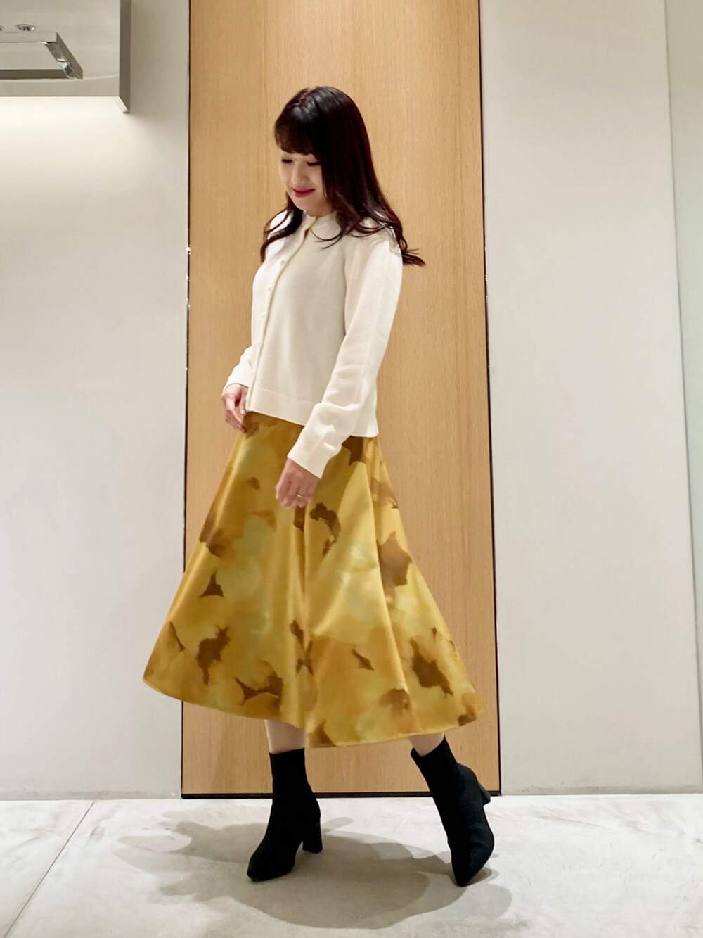 ホワイト系のカーディガン/ボレロ、イエロー系のスカートを着用したレディースの秋コーディネートの2枚目の写真