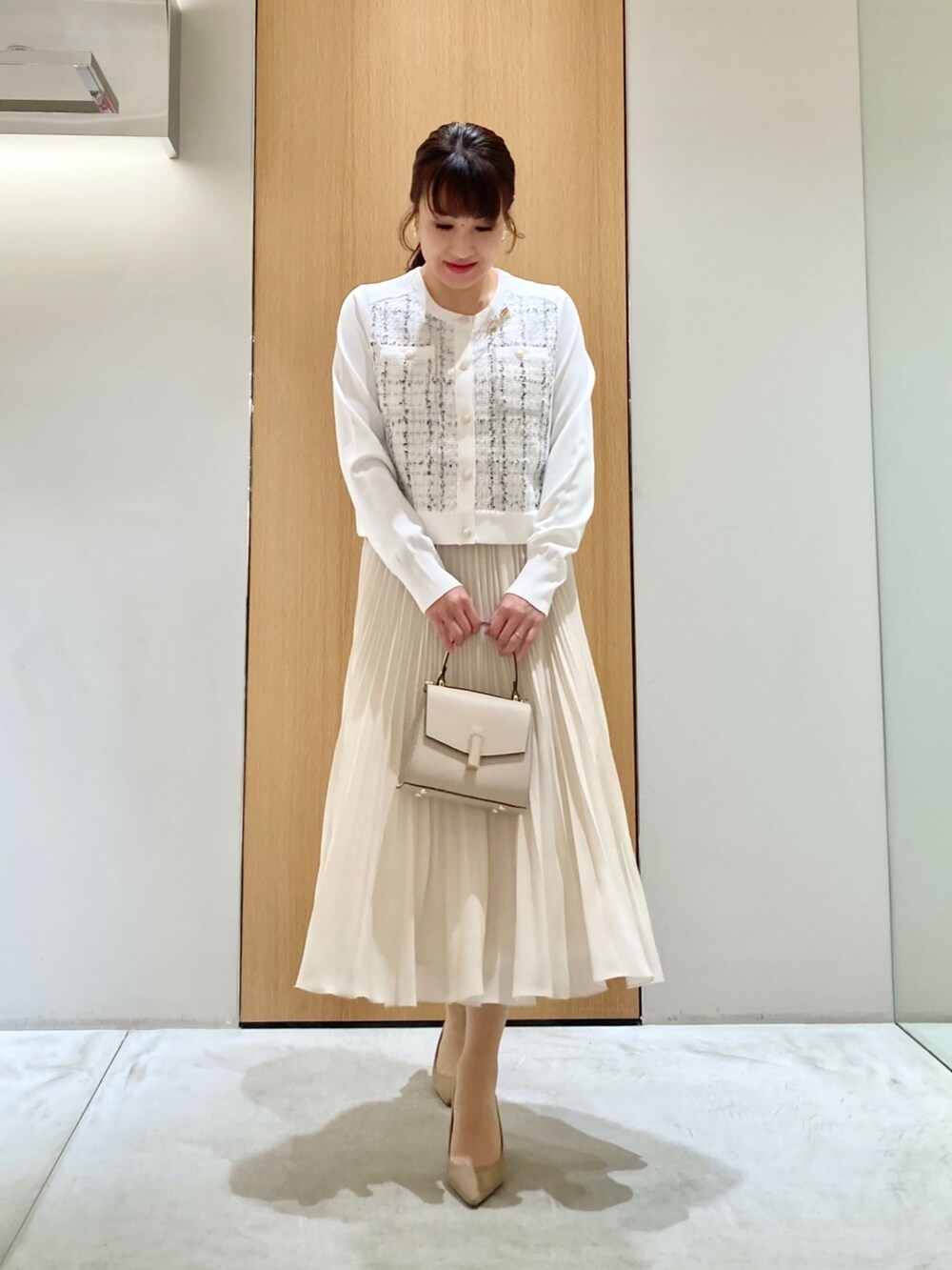ホワイト系のカーディガン/ボレロ、ベージュ系のトートバッグ、ホワイト系のスカートを着用したレディースの冬コーディネートの2枚目の写真