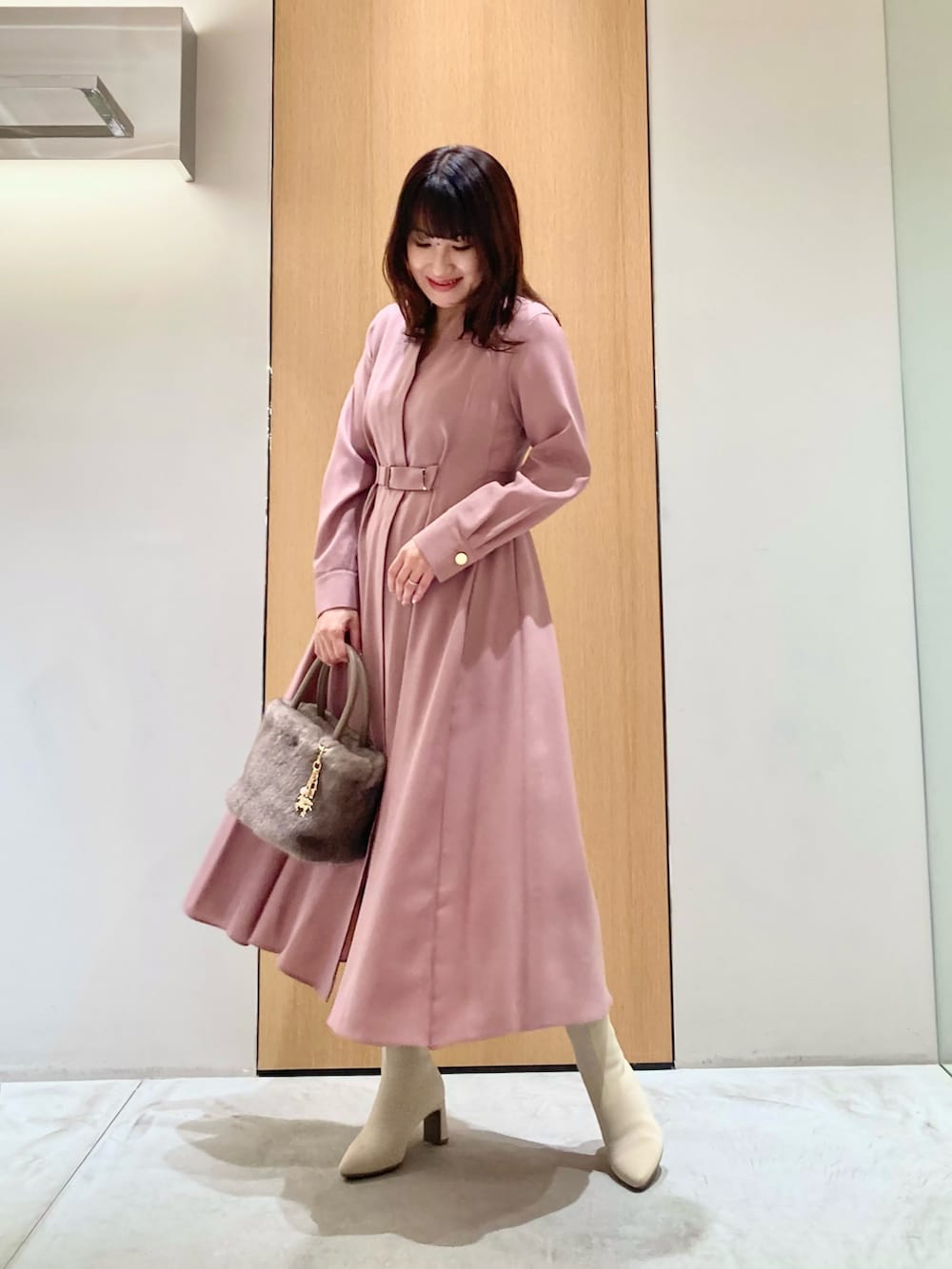 ピンク系のワンピース、ベージュ系のハンドバッグ、ゴールド系のリングを着用したレディースの秋コーディネートの2枚目の写真