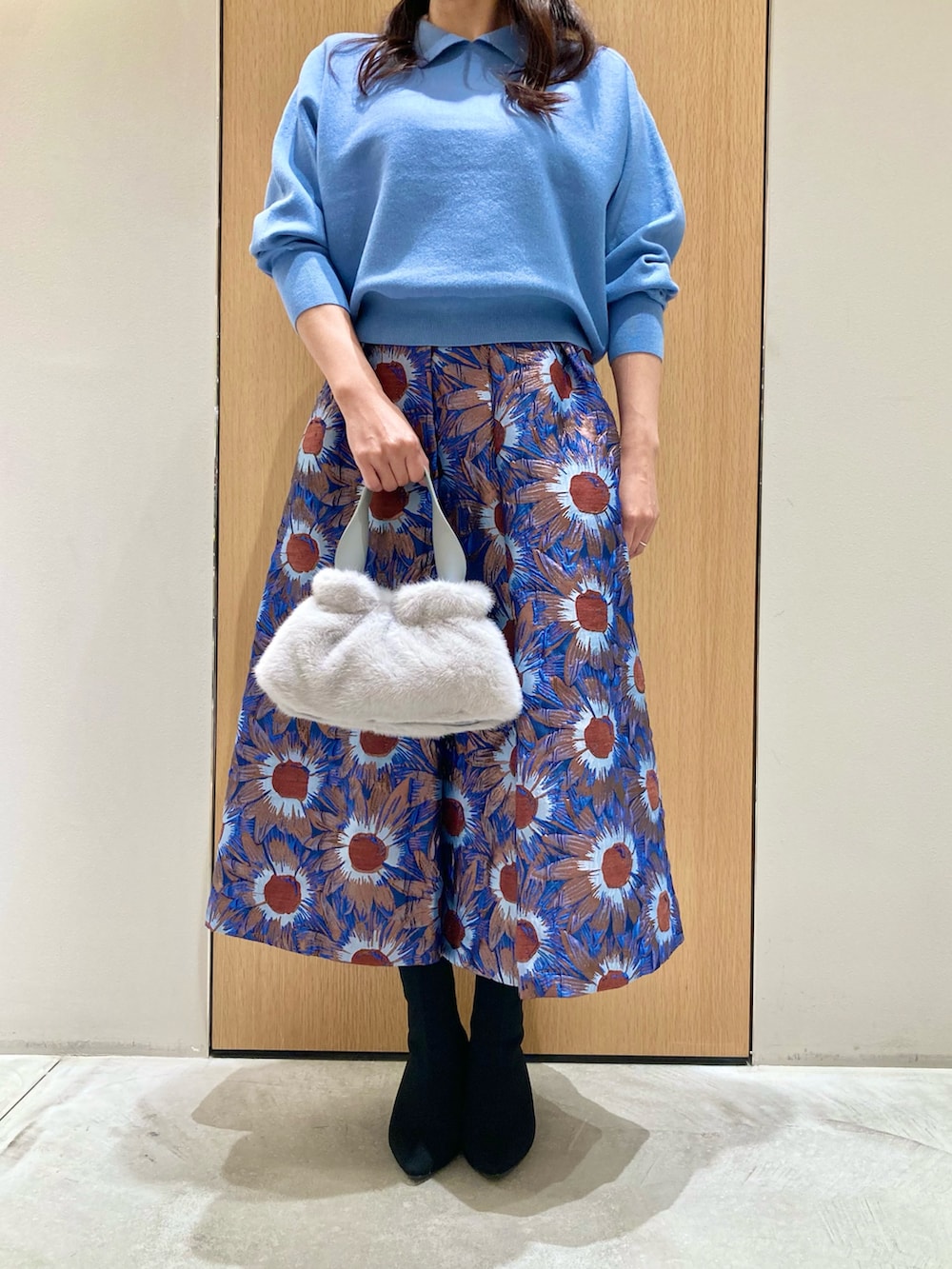 ブルー系のニット/セーター、ブルー系のハンドバッグ、ブルー系のスカートを着用したレディースの秋コーディネートの4枚目の写真