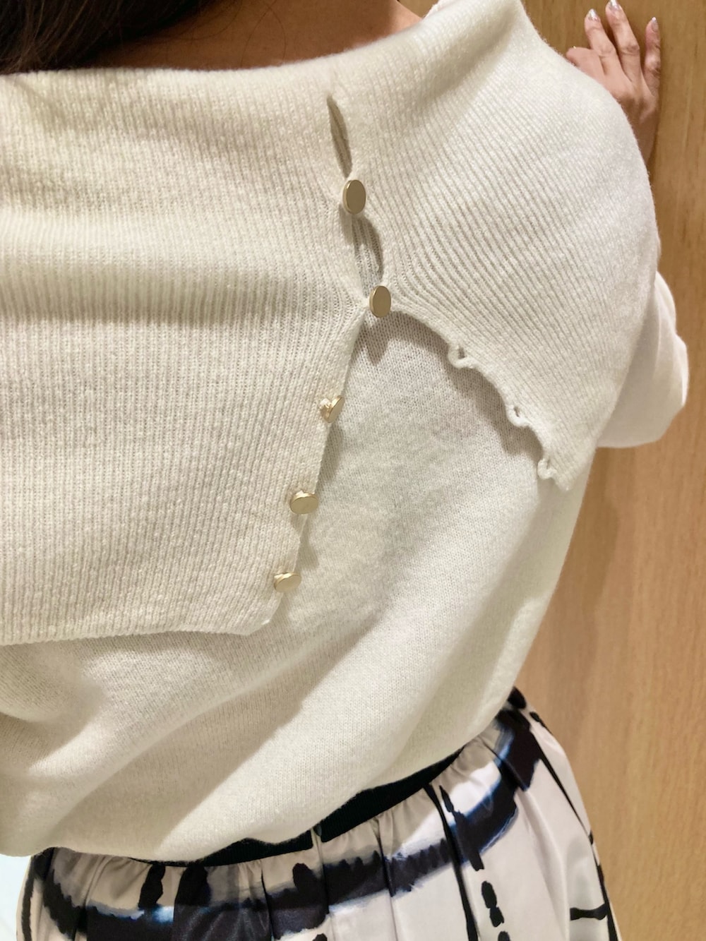 ホワイト系のニット/セーター、ホワイト系のスカート、ブラック系のイヤリングを着用したレディースの秋コーディネートの7枚目の写真