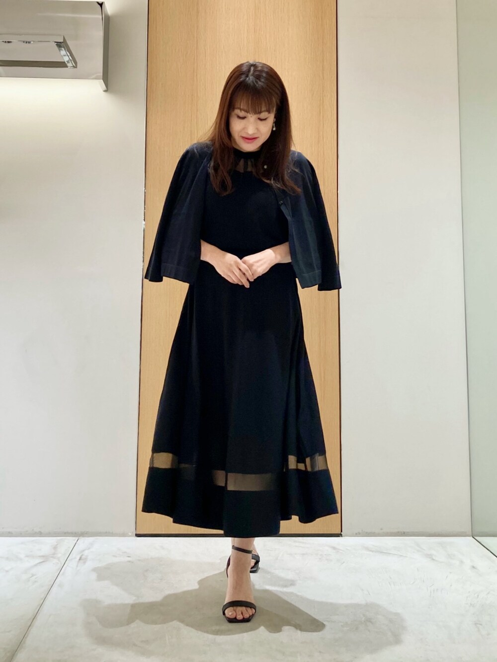 ブラック系のカーディガン/ボレロ、ブラック系のワンピース、ホワイト系のイヤリングを着用したレディースの春コーディネートの2枚目の写真