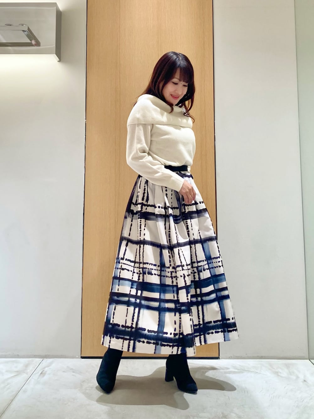 ホワイト系のニット/セーター、ホワイト系のスカート、ブラック系のイヤリングを着用したレディースの秋コーディネートの2枚目の写真