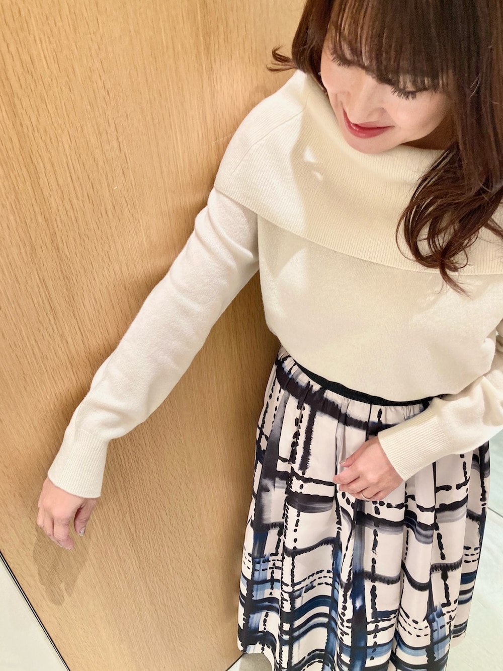 ホワイト系のニット/セーター、ホワイト系のスカート、ブラック系のイヤリングを着用したレディースの秋コーディネートの5枚目の写真