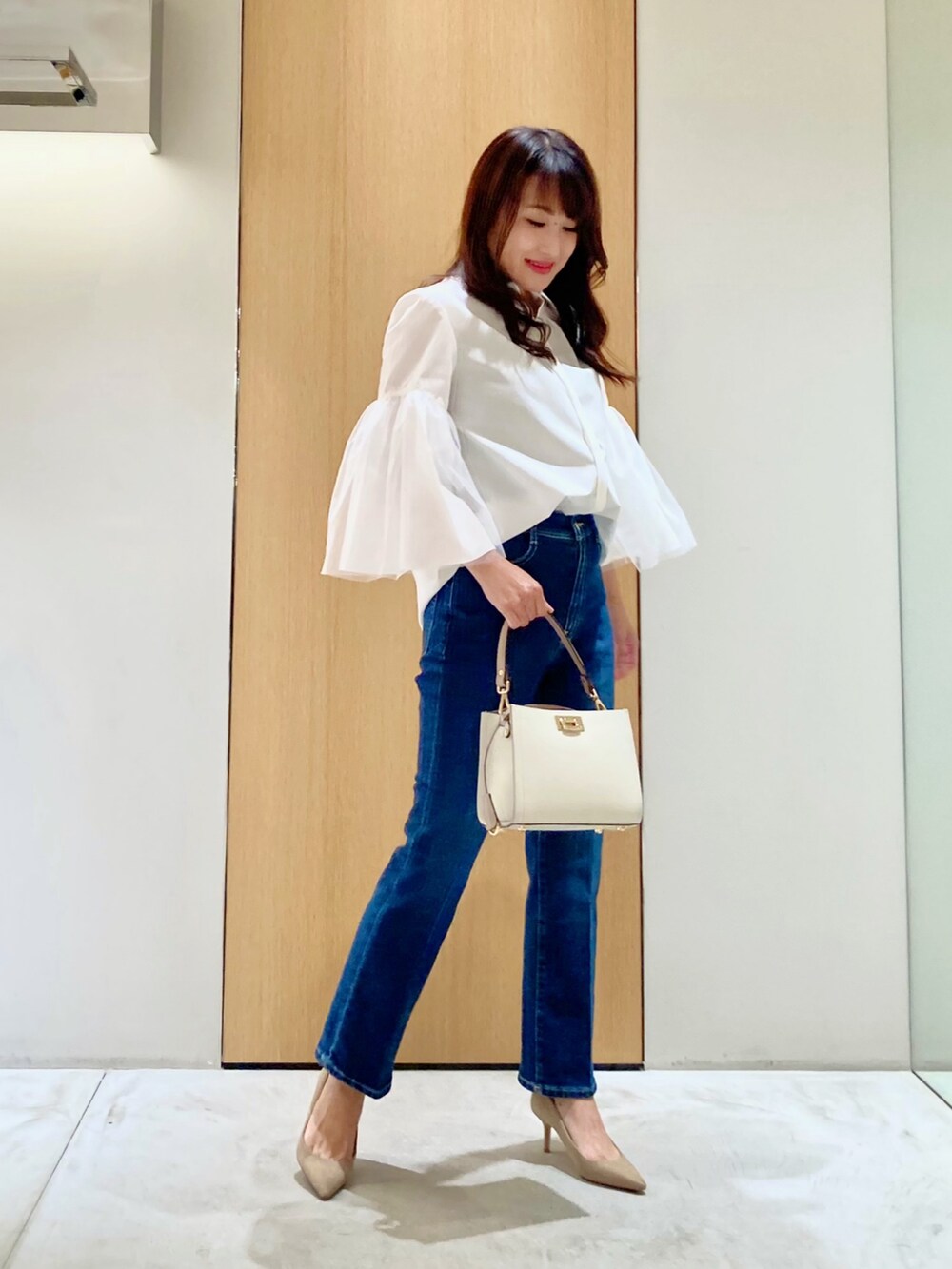 ホワイト系のシャツ/ブラウス、ホワイト系のハンドバッグ、ブルー系のデニムパンツを着用したレディースの秋コーディネートの2枚目の写真