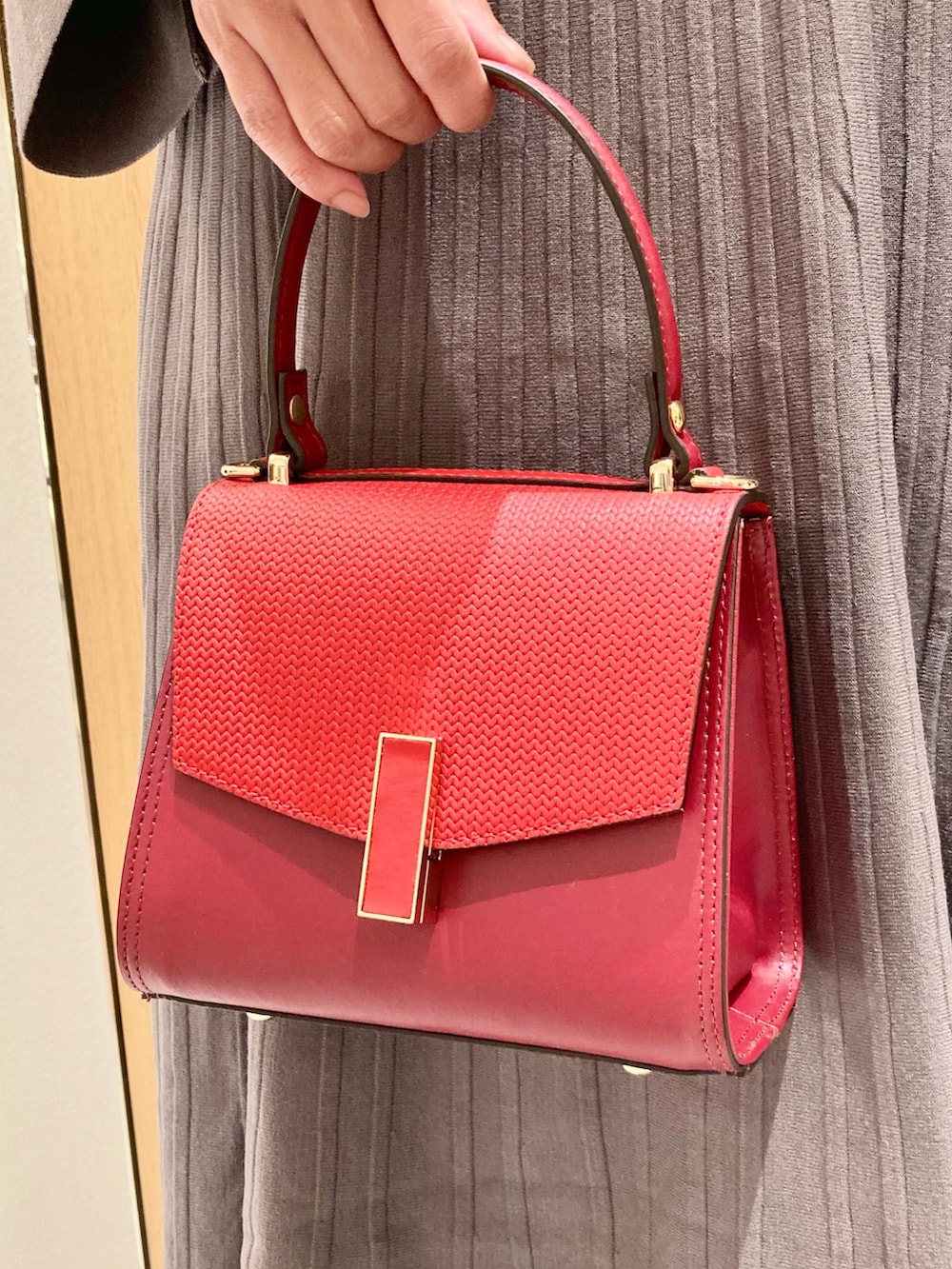 グレー系のワンピース、レッド系のハンドバッグを着用したレディースの秋コーディネートの9枚目の写真