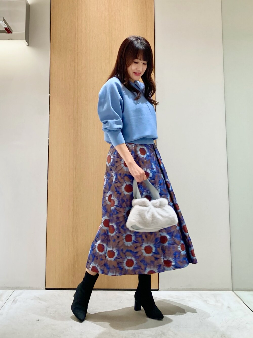 ブルー系のニット/セーター、ブルー系のハンドバッグ、ブルー系のスカートを着用したレディースの秋コーディネートの2枚目の写真