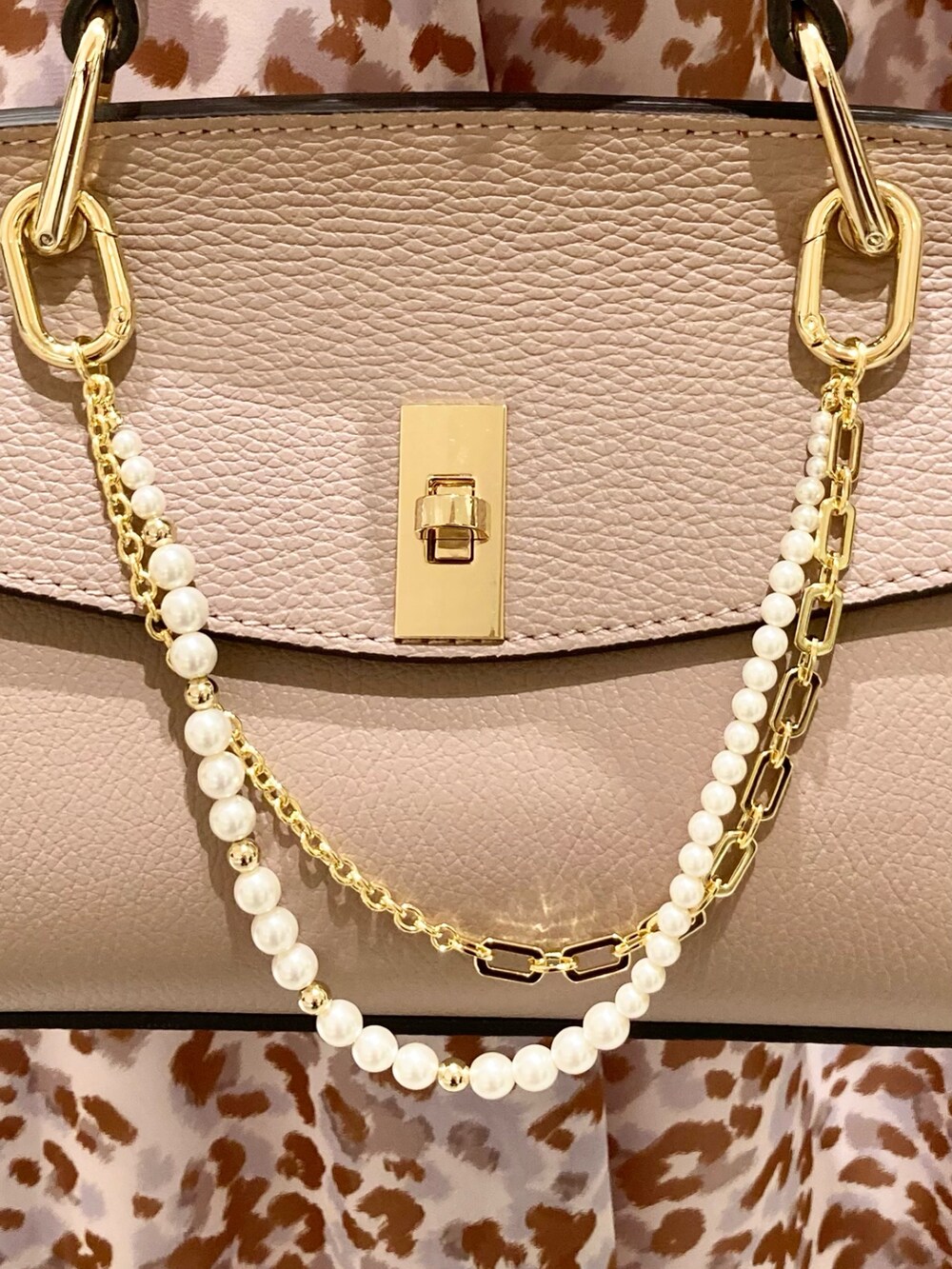 グレー系のワンピース、ピンク系のハンドバッグ、ゴールド系のリングを着用したレディースの秋コーディネートの8枚目の写真