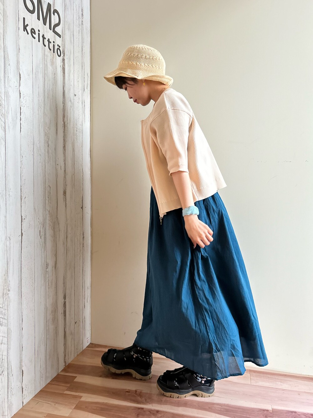 ホワイト系のカーディガン/ボレロ、ブルー系のワンピース、ブラック系のサンダルを着用したレディースの春コーディネートの2枚目の写真