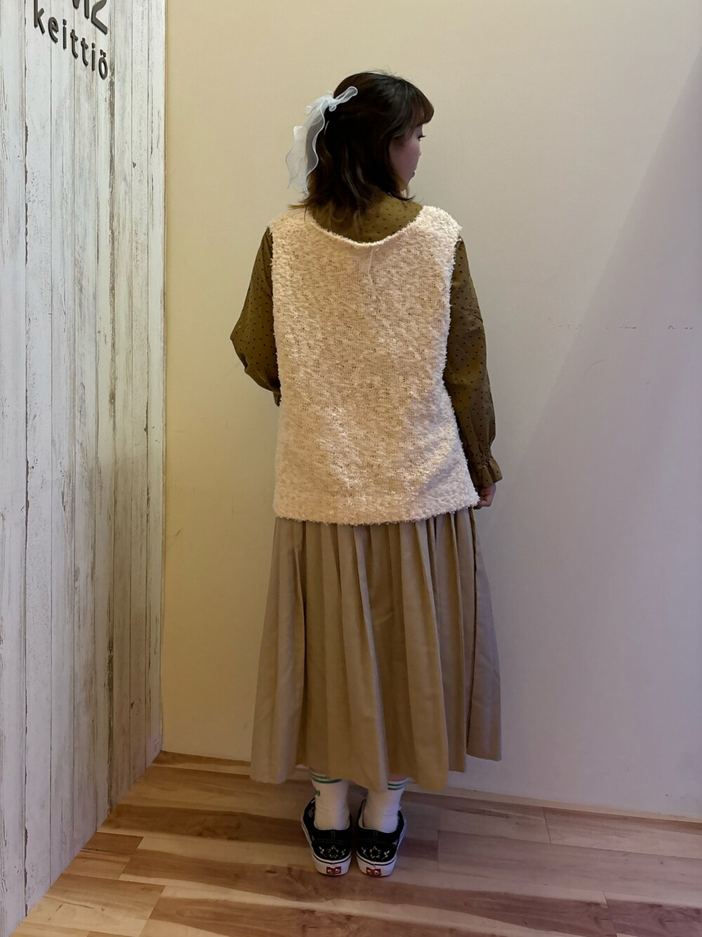 ベージュ系のスカート、イエロー系のシャツ/ブラウス、ホワイト系のベストを着用したレディースの秋コーディネートの3枚目の写真