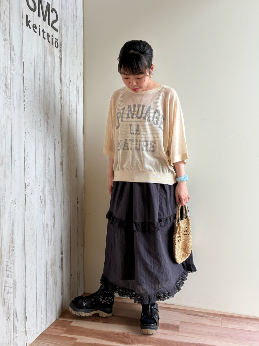 ゴールド系のハンドバッグ、ブラック系のスカート、グリーン系のニット/セーターを着用したレディースの春コーディネートの4枚目の写真