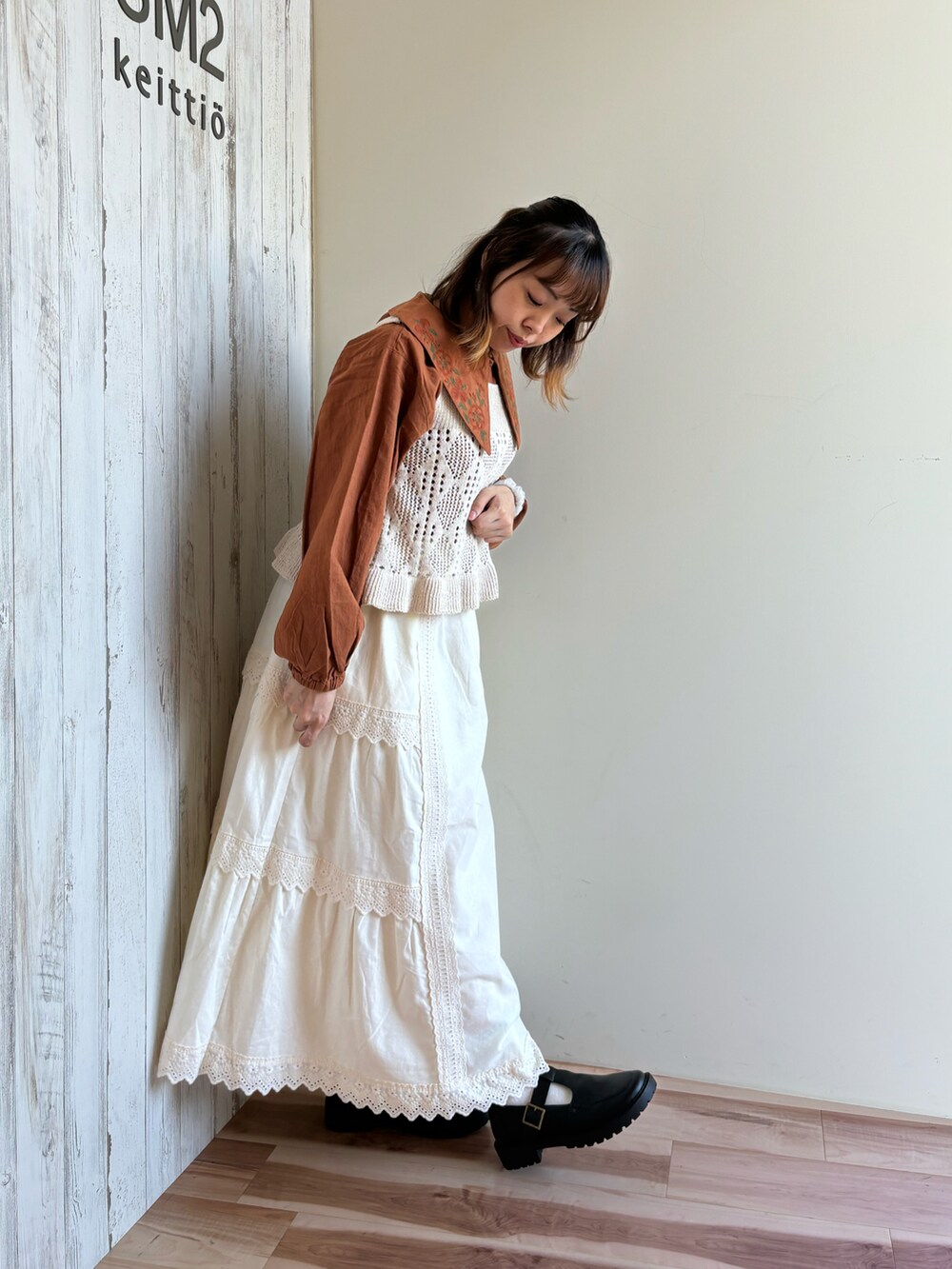 ホワイト系のベスト、ホワイト系のスカート、ブラック系のドレスシューズを着用したレディースの秋コーディネートの3枚目の写真