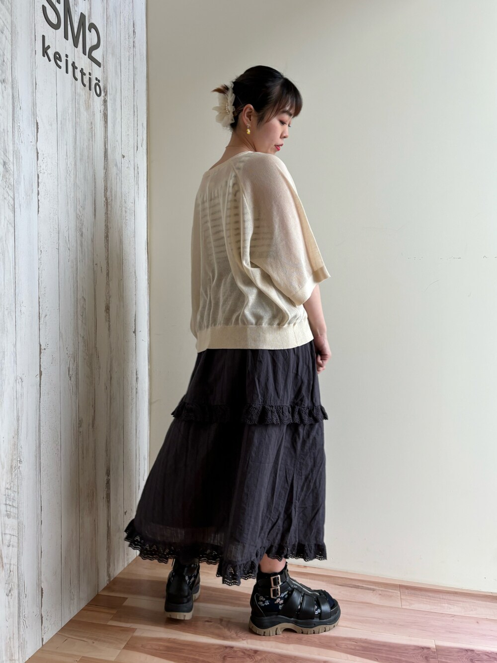 ゴールド系のハンドバッグ、ブラック系のスカート、グリーン系のニット/セーターを着用したレディースの春コーディネートの3枚目の写真