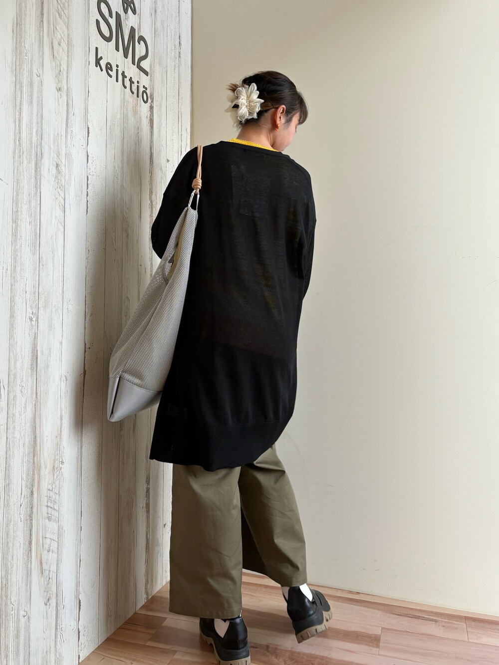 イエロー系のニット/セーター、ブラック系のカーディガン/ボレロ、グリーン系のその他パンツを着用したレディースの春コーディネートの3枚目の写真