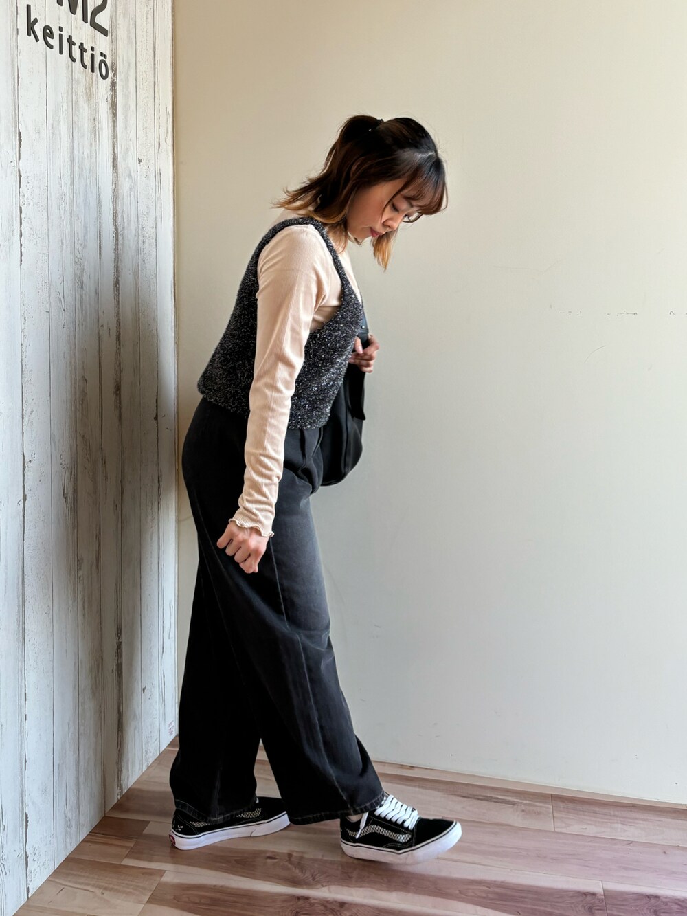 ベージュ系のTシャツ/カットソー、ブラック系のニット/セーター、ブラック系のハンドバッグを着用したレディースの秋コーディネートの2枚目の写真