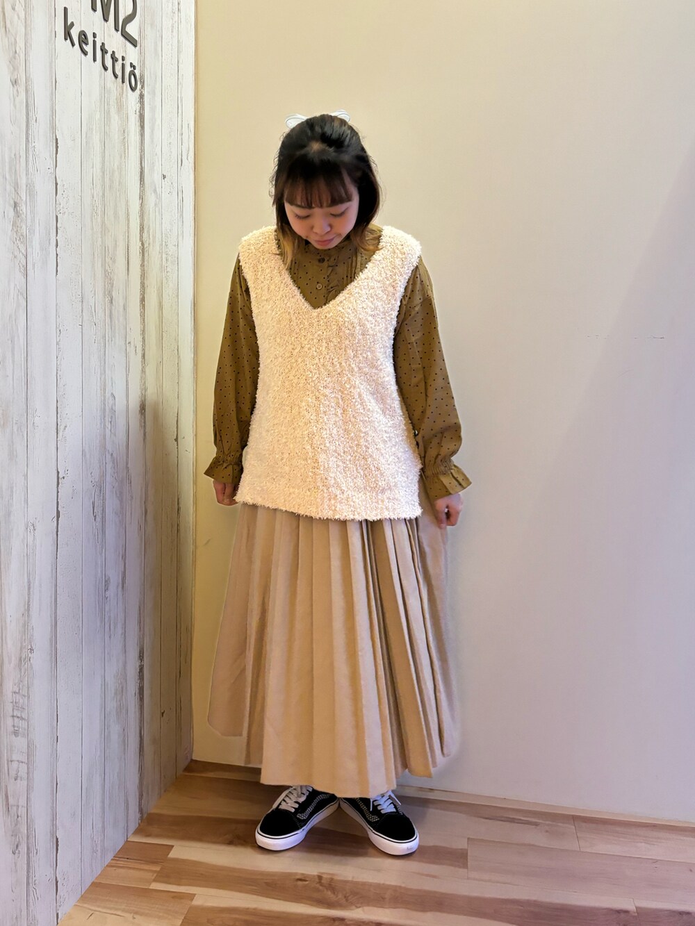 ベージュ系のスカート、イエロー系のシャツ/ブラウス、ホワイト系のベストを着用したレディースの秋コーディネートの2枚目の写真