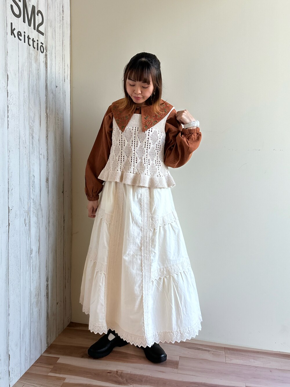 ホワイト系のベスト、ホワイト系のスカート、ブラック系のドレスシューズを着用したレディースの秋コーディネートの4枚目の写真