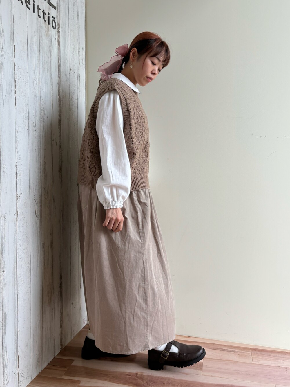 ブラウン系のベスト、ホワイト系のシャツ/ブラウス、ベージュ系のスカートを着用したレディースの秋コーディネートの3枚目の写真