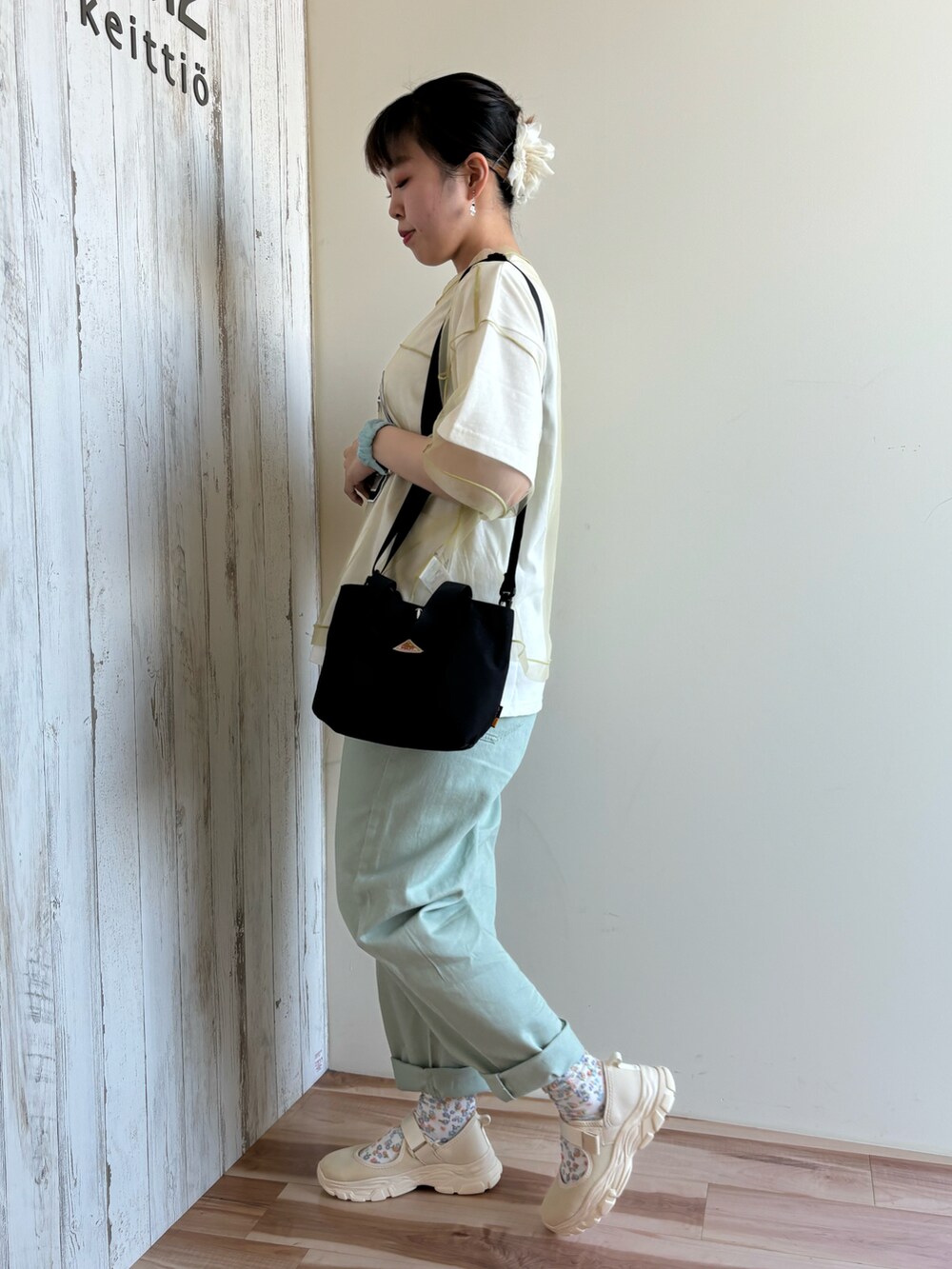 グリーン系のTシャツ/カットソー、グリーン系のパンツ、ブラック系のハンドバッグを着用したレディースの春コーディネートの2枚目の写真