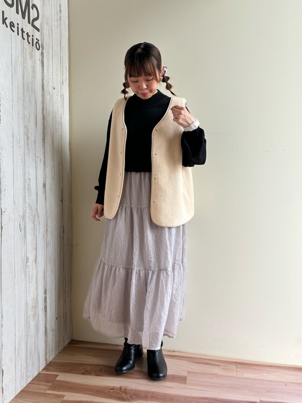 グレー系のスカート、ブラック系のドレスシューズ、グリーン系のニット/セーターを着用したレディースの秋コーディネートの4枚目の写真