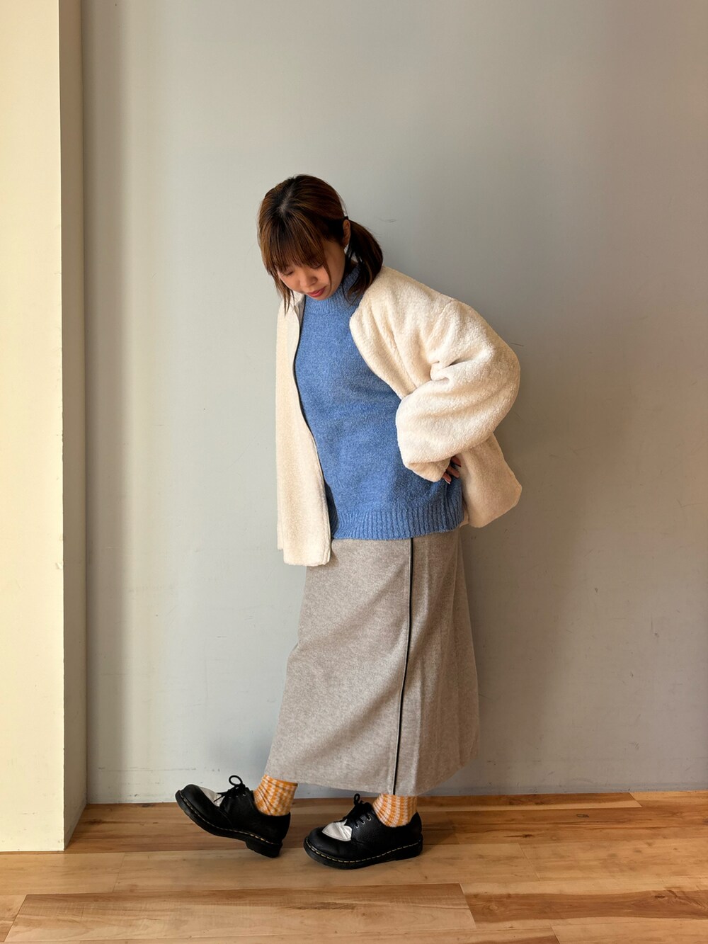 ブルー系のニット/セーター、ホワイト系のその他アウター、グレー系のスカートを着用したレディースの冬コーディネートの2枚目の写真