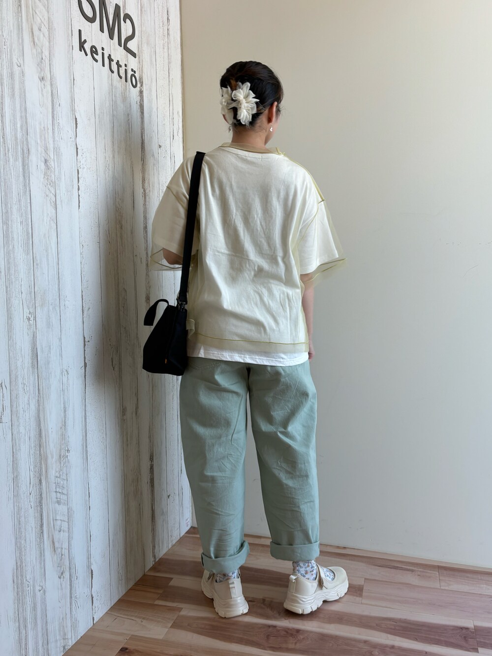 グリーン系のTシャツ/カットソー、グリーン系のパンツ、ブラック系のハンドバッグを着用したレディースの春コーディネートの3枚目の写真