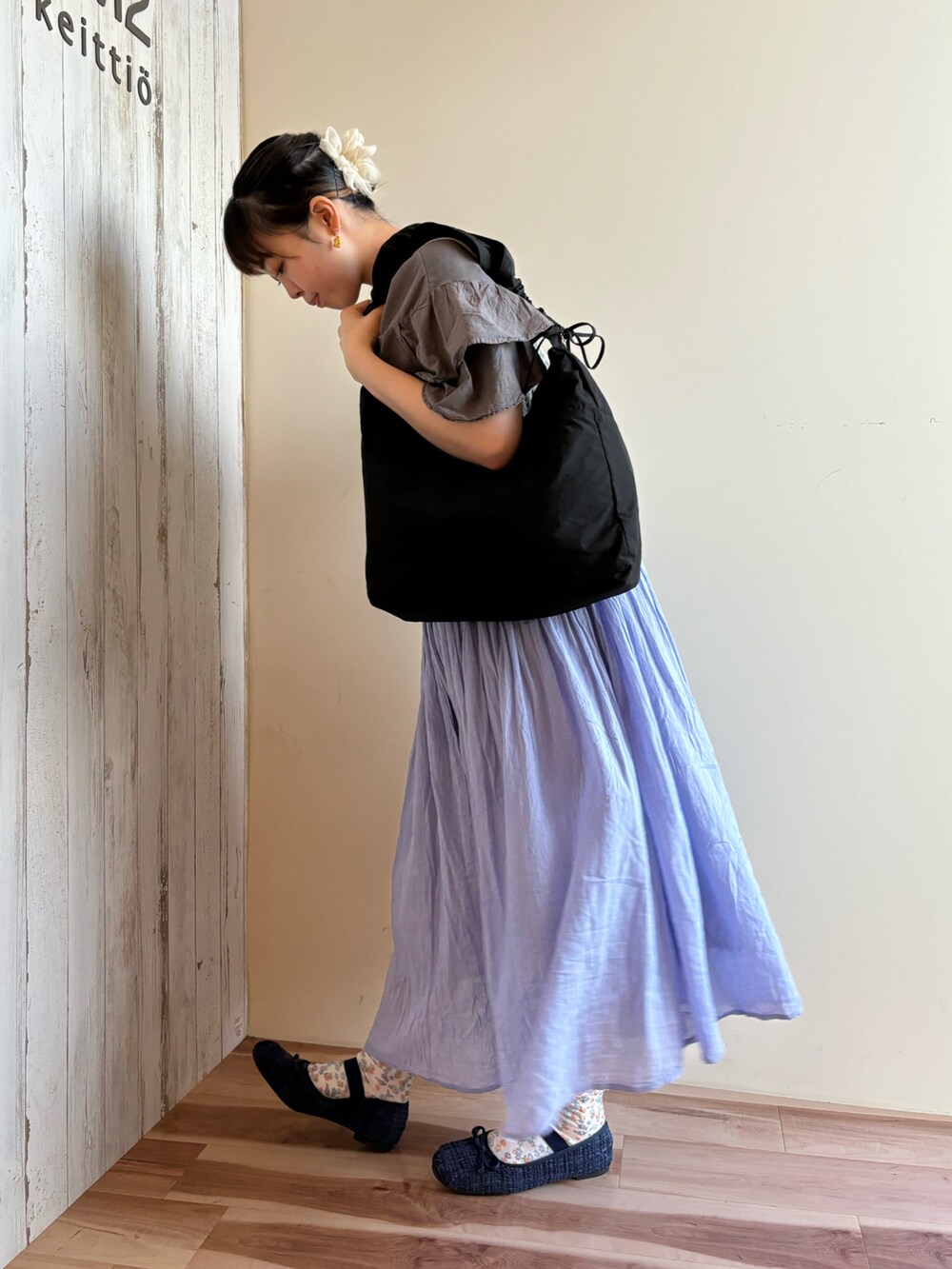 グレー系のTシャツ/カットソー、ホワイト系のニット/セーター、ブラック系のハンドバッグを着用したレディースの春コーディネートの2枚目の写真