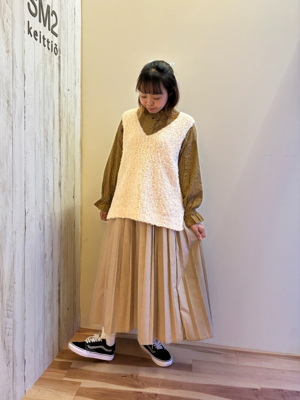 ベージュ系のスカート、イエロー系のシャツ/ブラウス、ホワイト系のベストを着用したレディースの秋コーディネートの4枚目の写真