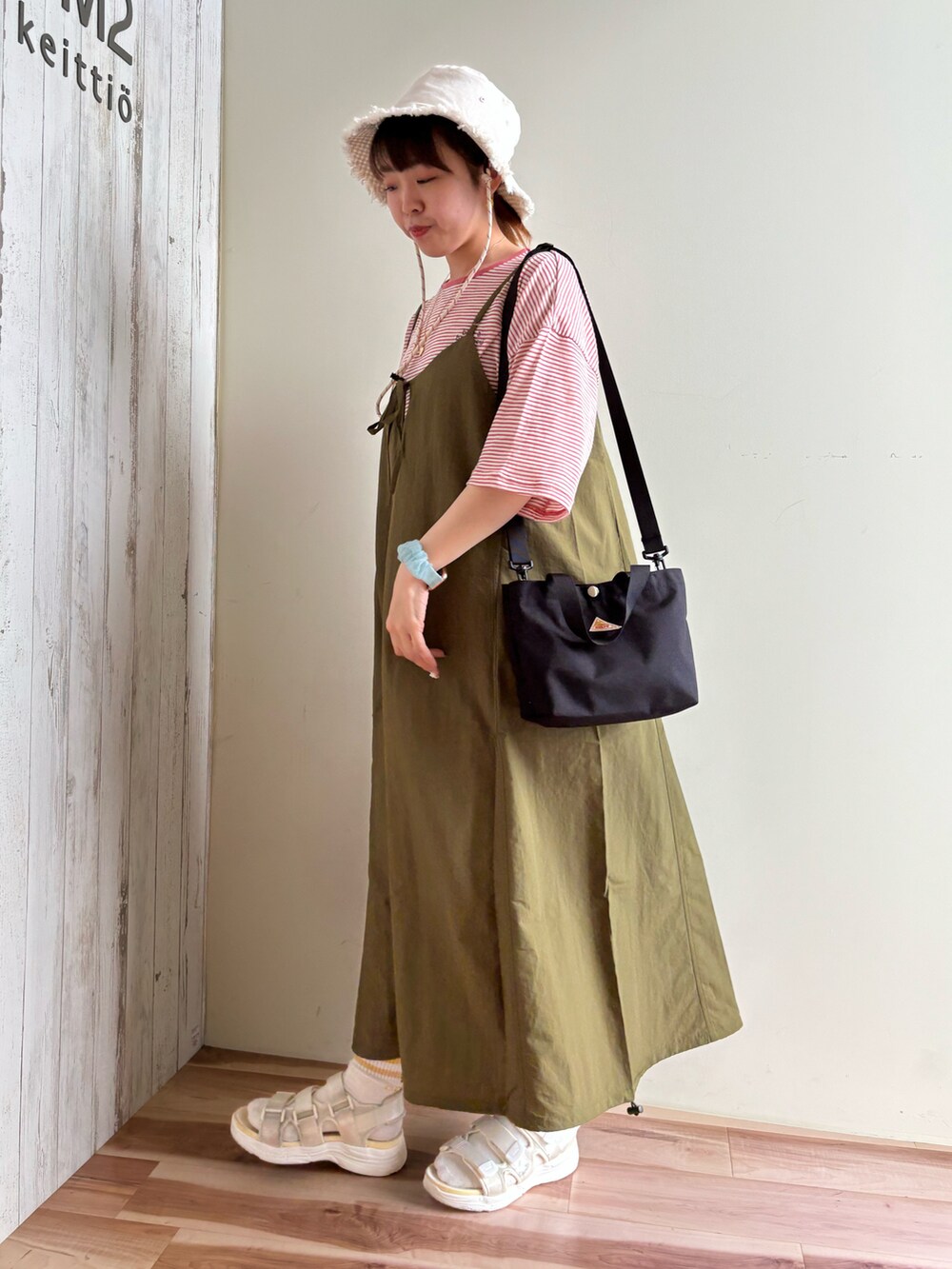 ピンク系のTシャツ/カットソー、グリーン系のワンピース/ドレス、ブラック系のハンドバッグを着用したレディースの春コーディネートの2枚目の写真