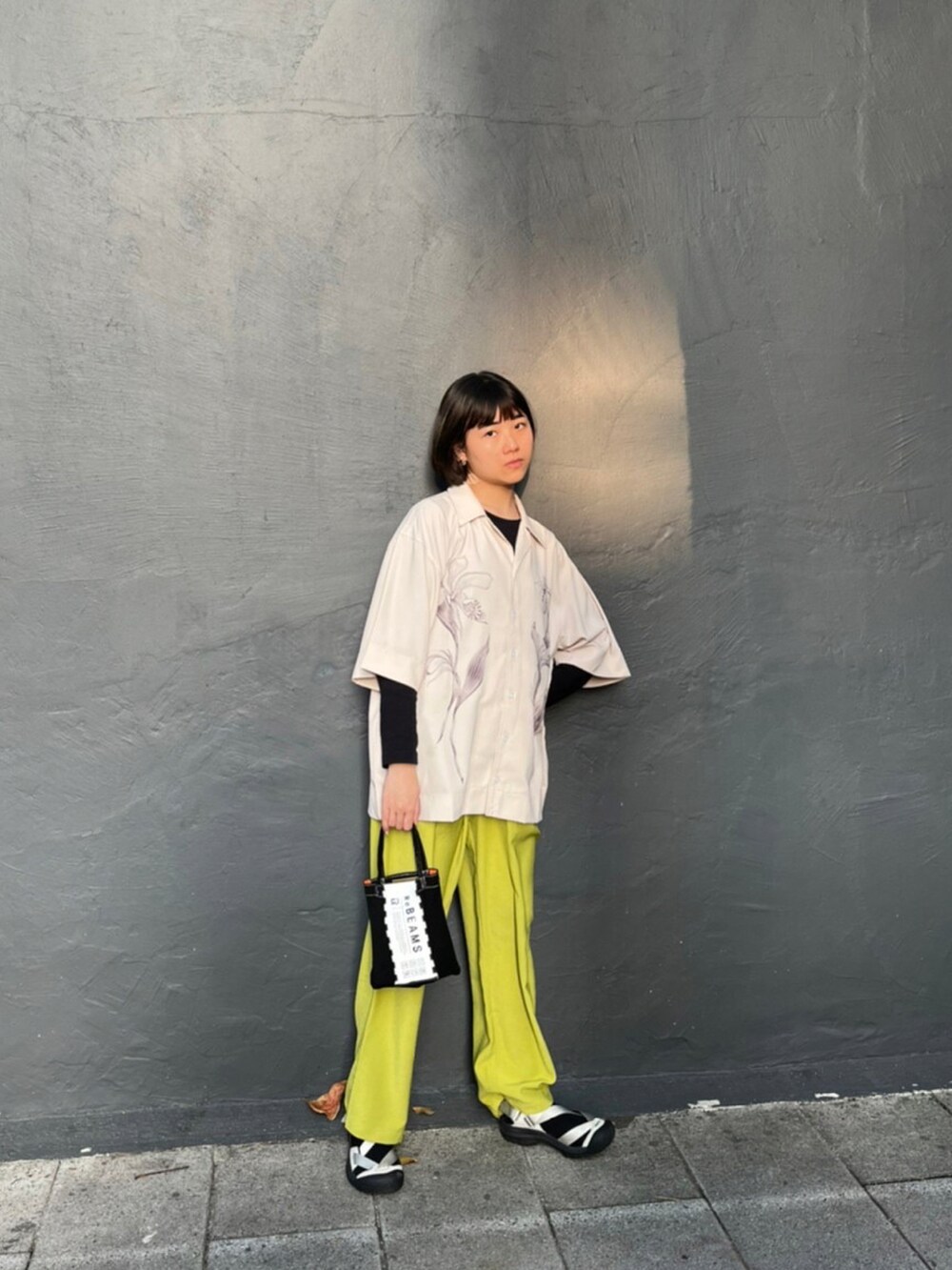 ブラック系のトートバッグ、ホワイト系のサンダル、ベージュ系のシャツ/ブラウスを着用したレディースの春コーディネートの2枚目の写真