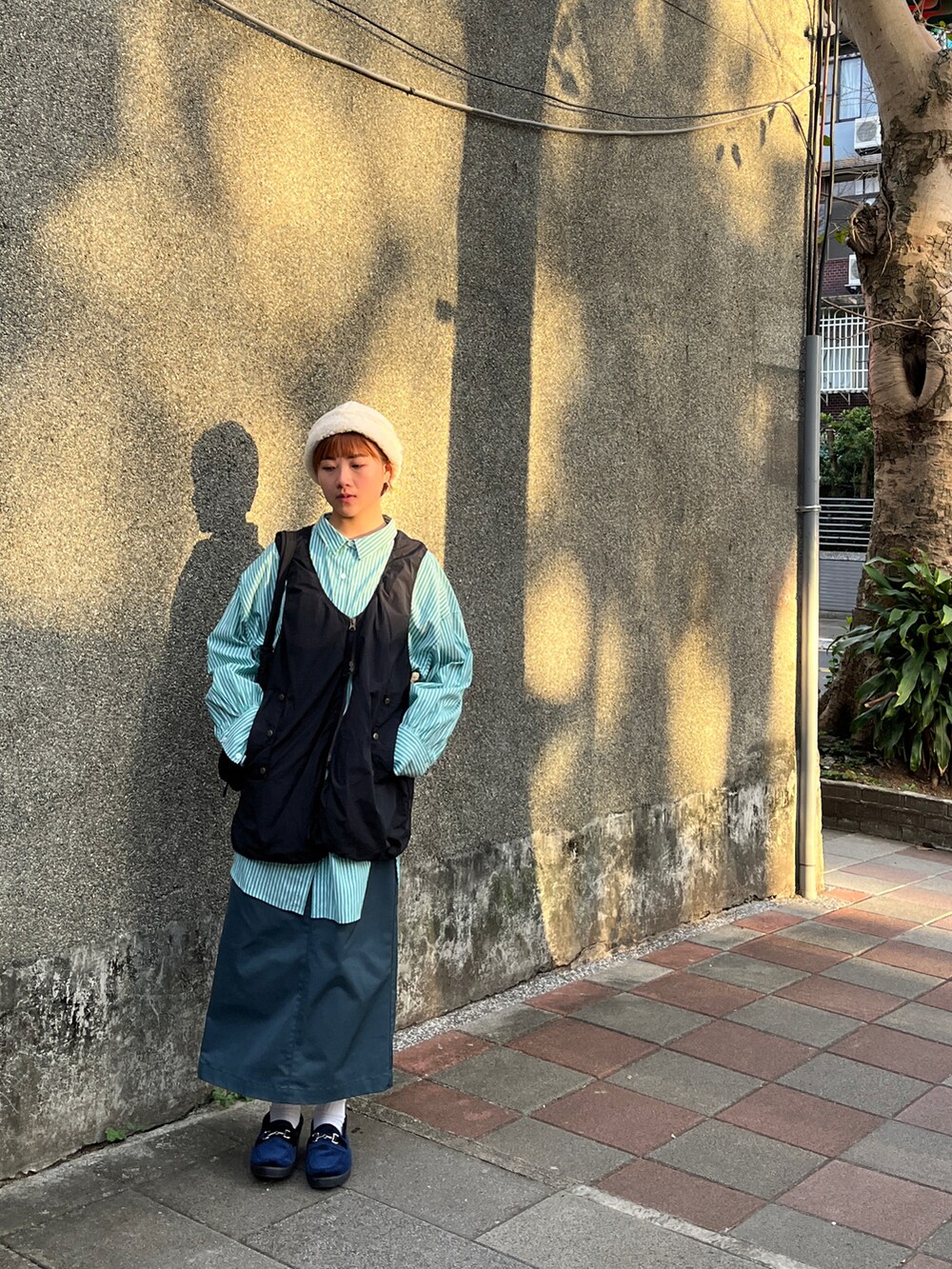 ブラック系のベスト、グリーン系のスカート、ブルー系のローファーを着用したレディースの夏コーディネートの2枚目の写真