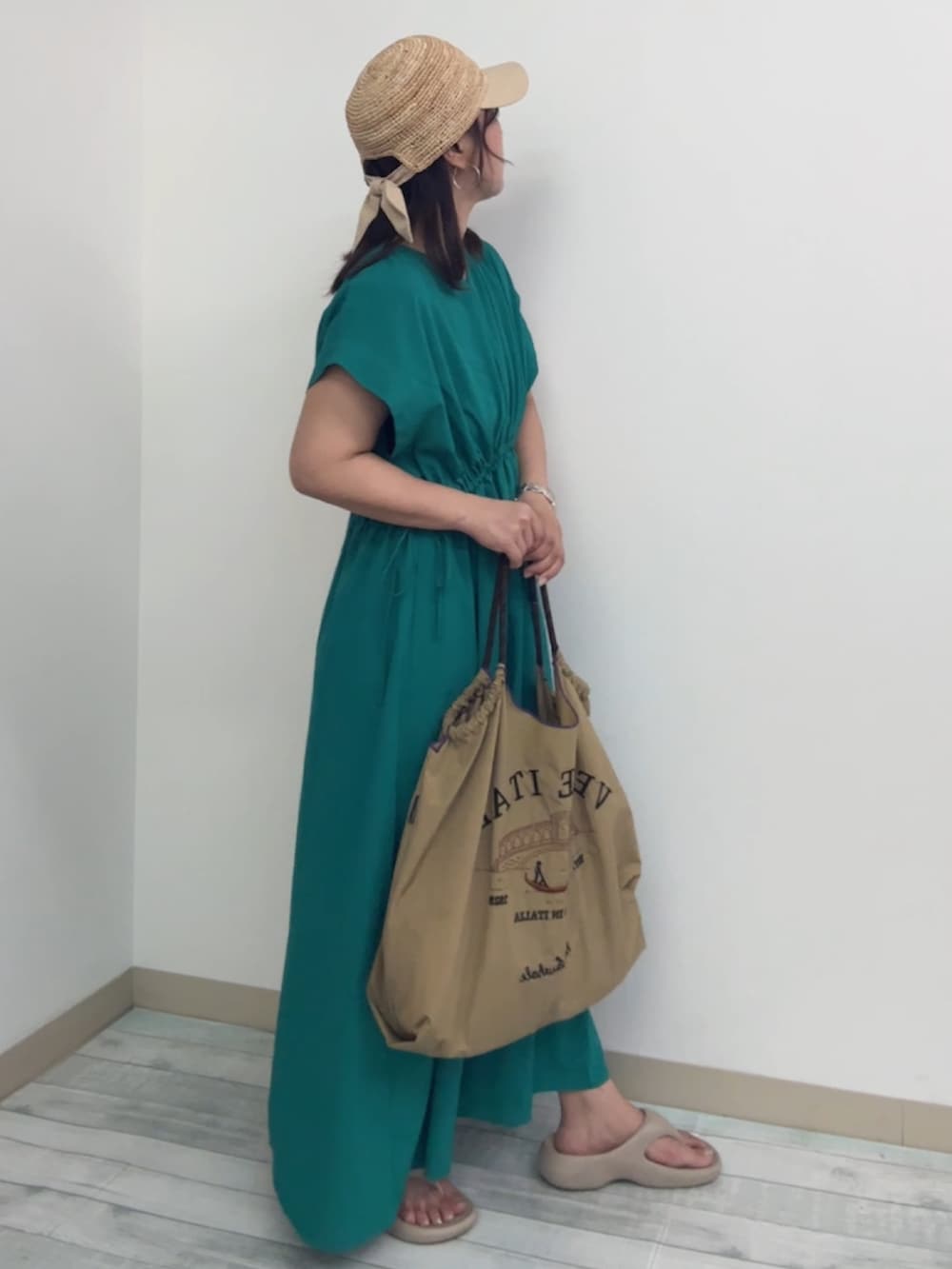 ベージュ系のハンドバッグ、グリーン系のワンピース、ベージュ系のビーチサンダルを着用したレディースの夏コーディネートの3枚目の写真