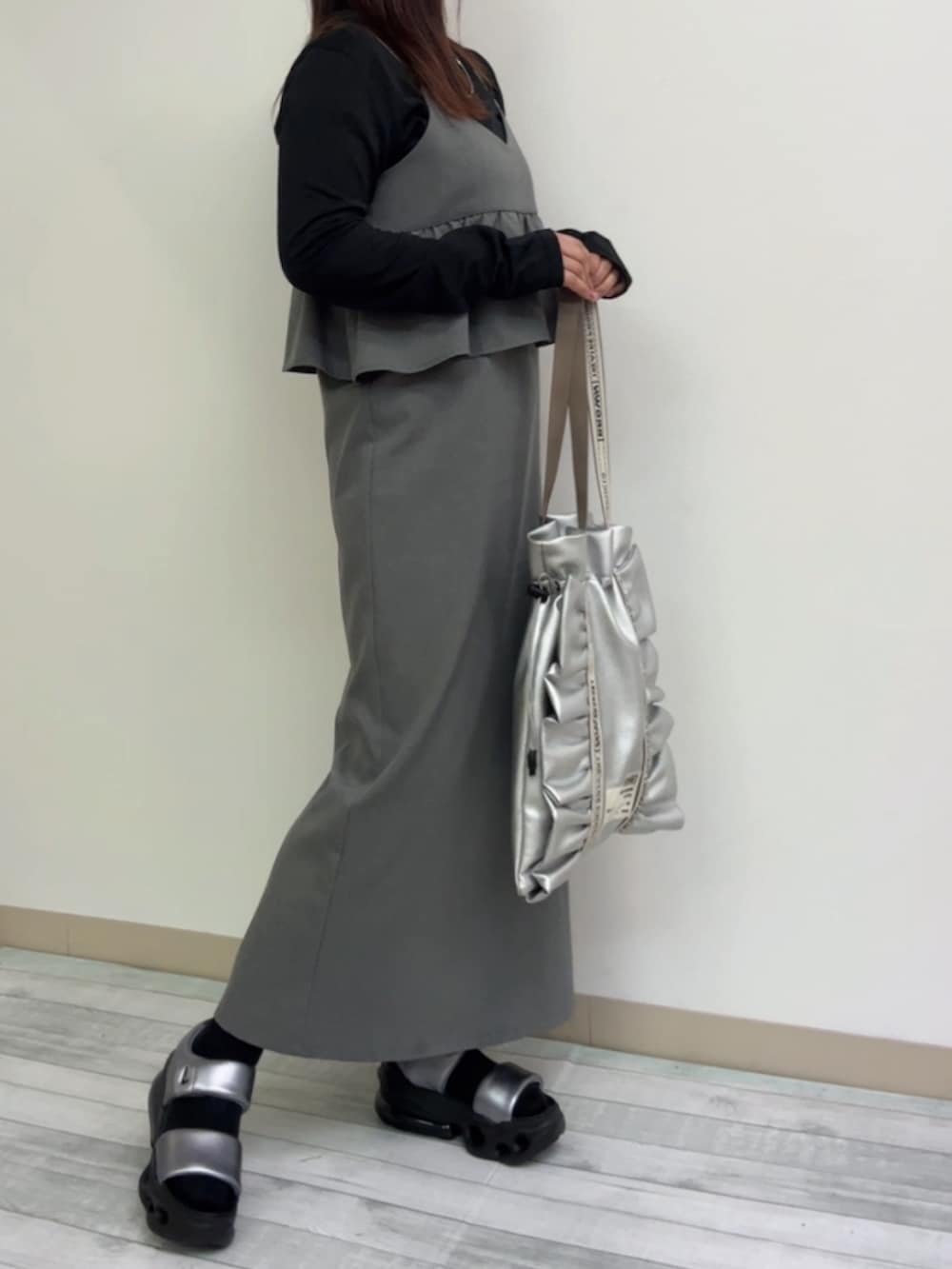グレー系のジャンパースカート、シルバー系のトートバッグ、シルバー系のサンダルを着用したレディースの春コーディネートの2枚目の写真