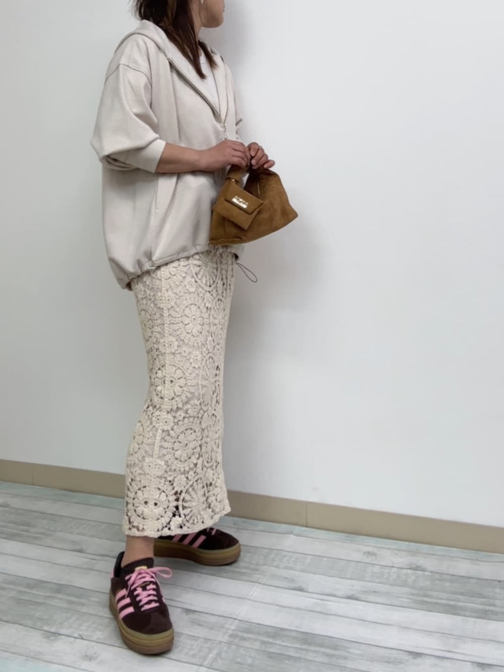 ブラウン系のスニーカー、ホワイト系のパーカー、ベージュ系のスカートを着用したレディースの春コーディネートの2枚目の写真