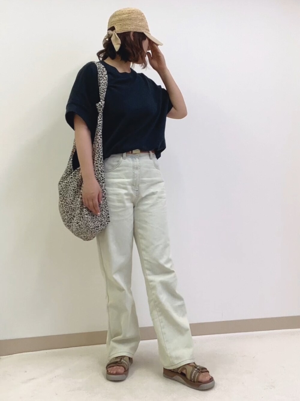 ホワイト系のデニムパンツ、ブラック系のショルダーバッグ、ブラック系のTシャツ/カットソーを着用したレディースの春コーディネートの2枚目の写真