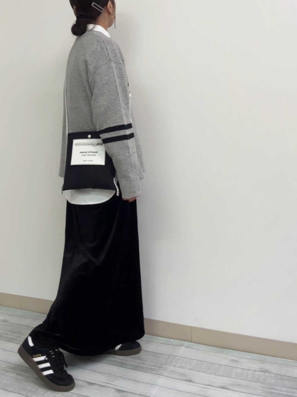 グレー系のニット/セーター、ブラック系のスニーカー、ホワイト系のシャツ/ブラウスを着用したレディースの冬コーディネートの2枚目の写真
