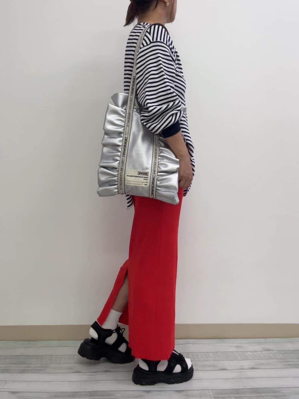 ブラック系のトップス、レッド系のスカート、ブラック系のサンダルを着用したレディースの秋コーディネートの2枚目の写真