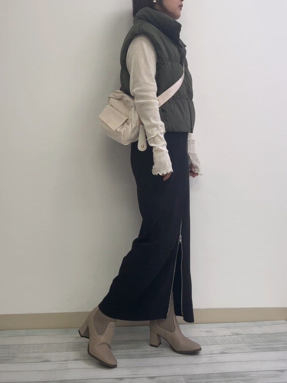 ブラック系のスカート、ベージュ系のブーツ、ホワイト系のショルダーバッグを着用したレディースの秋コーディネートの2枚目の写真