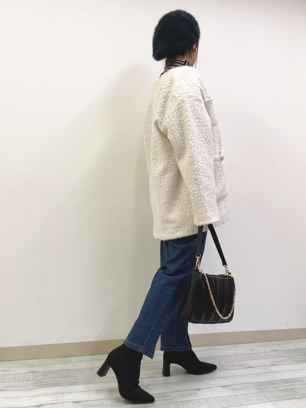 ブラック系のニット/セーター、ホワイト系のノーカラーコート、ブルー系のデニムパンツを着用したレディースの冬コーディネートの2枚目の写真